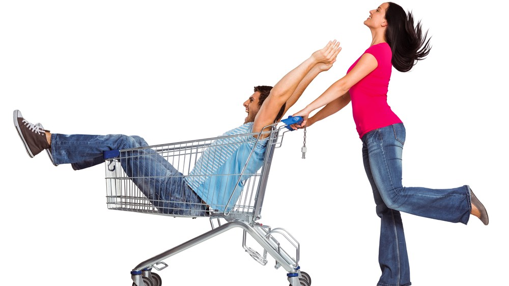 woman pushing man in shopping cart